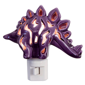 The DINOSAUR NIGHTLIGHT by LILY'S LIGHTS is a purple ceramic stegosaurus-shaped nightlight that emits a warm glow through its cutout patterns. This handmade creation boasts quality craftsmanship, featuring a spiked back and standing on a white plastic plug base, suitable for standard electrical outlets. It's perfect for unique gifts.