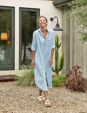 The FRANK & EILEEN Rory Maxi Shirtdress in Famous Denim is a full-length button-up dress featuring a collar, rolled-up sleeves to mid-length, and a single chest pocket. Its sleek, minimalist design embodies that California chic look against a plain white textured background.