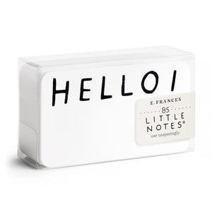 A clear plastic box contains a stack of small notecards. The top card showcases "HELLO!" in bold, black letters, while the box's label, featuring a watercolor illustration, reads "E.FRANCES PAPER HELLO LITTLE NOTES 85 use unsparingly.