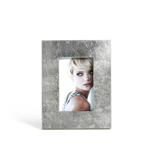 The ZODAX SILVER LEAF PHOTO FRAME - 4x6 features a sleek silver finish, ideally suited for displaying portraits such as one of a person with short blonde hair and a thoughtful expression gazing over their shoulder.