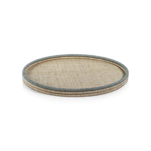 The COILED RATTA & ABACA ROUND TRAY by ZODAX, featuring a woven design with abaca and a contrasting blue edge, rests elegantly against a white background.