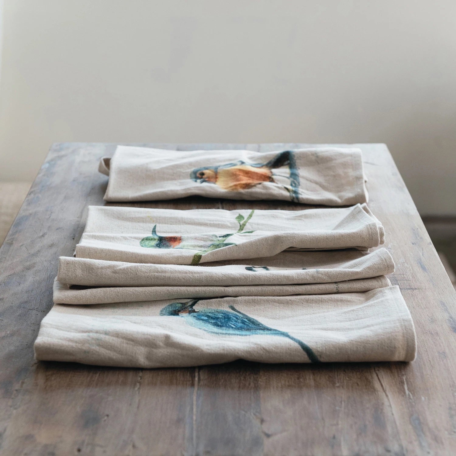 The TEA TOWEL WITH BIRD by CREATIVE COOP features four charming bird illustrations on premium cotton and linen fabric. One tea towel shows a bird perched on a branch, another depicts a bird standing tall, the third illustrates a small bird, and the last one showcases a bird perching delicately on a twig. Each printed tea towel displays birds facing outward.