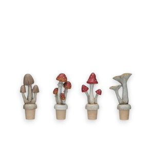 Four **CREATIVE COOP RESIN MUSHROOM BOTTLE STOPPERS**, available in four unique styles with red spotted and brown-capped varieties, are displayed against a white background.