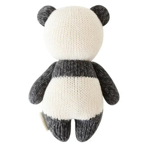 Introducing the CUDDLE + KIND - HANDMADE BABY PANDA from CUDDLE & KIND, a charming, hand-knit plush toy featuring gray ears, arms, and legs, and a white body accented with gray around the eyes and limbs. The panda's smiling face and black eyes add to its adorable appeal. This lovely toy is perfect for baby shower gifts, crafted with love to support fair trade income initiatives.