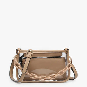 Introducing the CLEAR CROSSBODY BAG by JEN & CO: A stylish handbag crafted from vegan leather, showcasing a layered beige design with an open top and a visible zipper pocket. This bag is elegantly framed by a transparent outer layer and is complemented by a chunky beige chain strap for additional style and versatility.