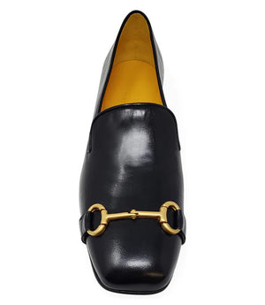 The Madison Maison Square Toe Loafer in gold metallic showcases its handmade craftsmanship and 100% leather composition. This single loafer, characterized by a low wooden heel and square toe, is adorned with a decorative gold buckle on the front. The opulent gold interior lining enhances its luxurious appeal, elegantly displayed in a side profile view against a plain white background.