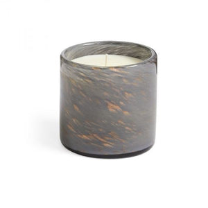 The LAFCO - FEU DE BOIS HOLIDAY CANDLE 6.5OZ is a stylish gray glass candle holder featuring a marbled texture, with a single white soy wax candle inside and delicate bronze swirls adorning the glass.