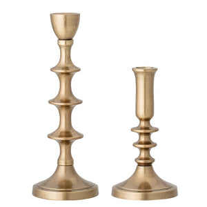 Two aluminum taper candle holders, both from Creative Coop, are shown against a white background. The candlestick on the left is taller and features an intricate, vintage design with multiple curves, identified as the Aluminum Taper Candle Holder (Large), while the shorter one on the right boasts a simpler style reminiscent of an antique gold candle holder.