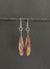 The ANN LIGHTFOOT Mookite Drop Earrings boast a long, teardrop shape with a stunning marbled design in vibrant red and white hues. Mounted on sterling silver hooks, they are beautifully showcased on a pristine white background.