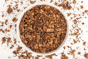 A black package of STRUESLI - CACAO + COFFEE GRANOLA against a white background. The front of the package lists features such as tiger nuts, pecans, walnuts, prebiotic, no sweeteners, no grains, and artisan coffee. Text at the bottom mentions that the organic granola is plant-based and keto-friendly.