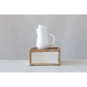 A STONEWARE CHICKEN CREAMER by CREATIVE COOP sits on a small, rustic wooden box against a gray background. Its wavy, crown-like rim is showcased beautifully, making it the perfect addition to any elegant home collection.