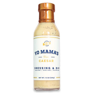 A bottle of YO MAMA'S FOODS' Classic Caesar dressing and dip. The label indicates it is gluten-free, dairy-free, and contains no added sugar. The bottle holds 13 ounces (369 grams) of product. The label features a minimalistic design with a white background and blue and gold accents.