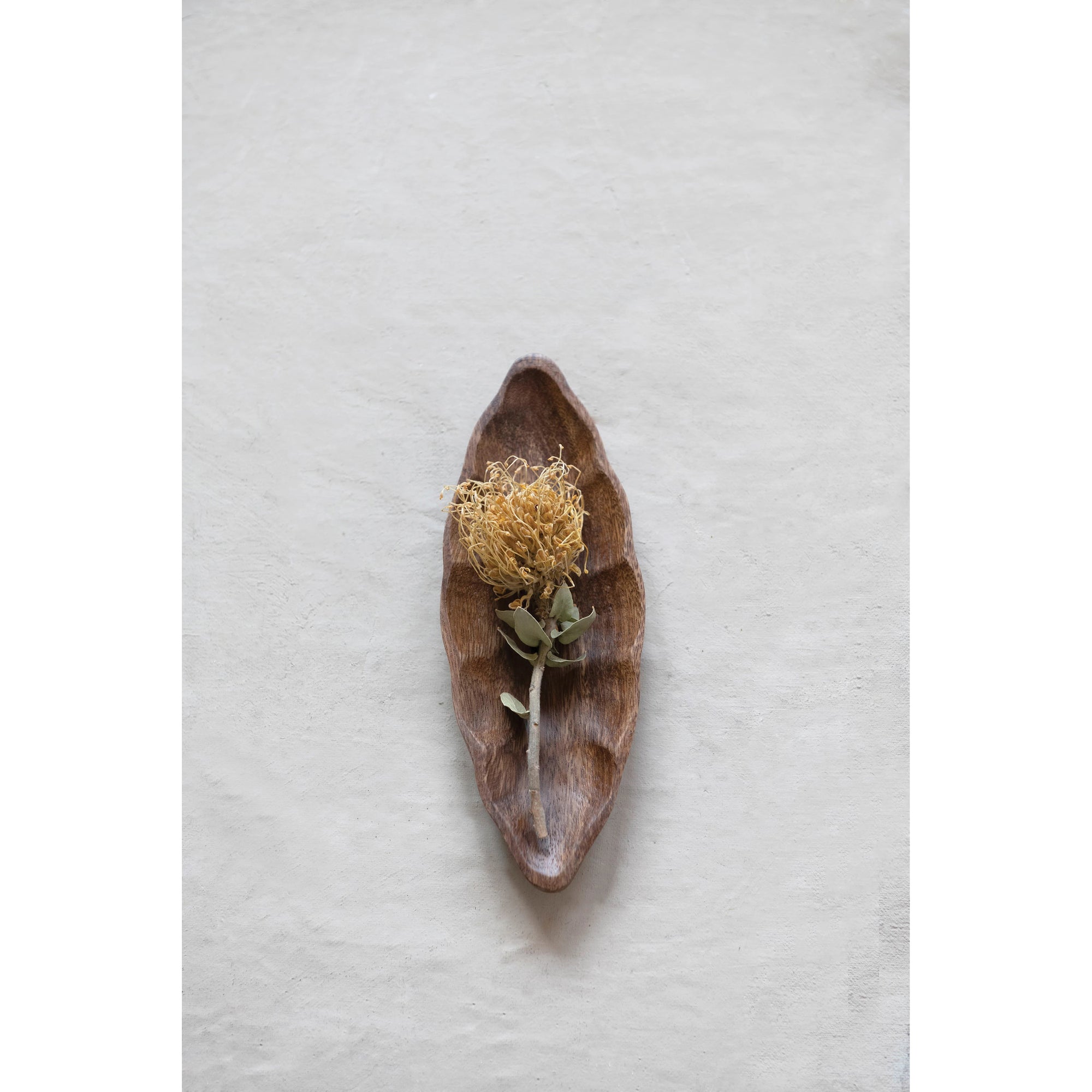 The ACACIA WOOD LEAF DISH by CREATIVE COOP is a leaf-shaped wooden tray with textured brown surface and wavy edges, made from exquisite acacia wood. Perfect for serving or decoration, this hand-carved piece adds nature's elegance to any setting.