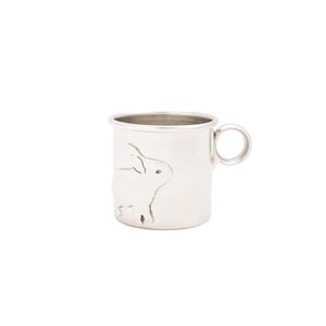 The PEWTER BABY CUP - RABBIT by BEEHIVE HANDMADE is a small, heirloom-quality cup featuring an etched design of a rabbit on its surface. The cup has a simple, rounded handle and a minimalist appearance. This vintage-inspired baby cup depicts the rabbit in a standing pose facing forward.