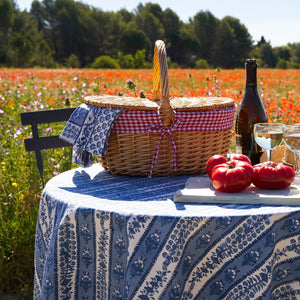 The PROVENCE AVIGNON TABLECLOTH 59X59 by COULEUR NATURE showcases French elegance with hand-printed blue and white linens, featuring a central vertical stripe design adorned with floral motifs and completed by a dense geometric border for an intricate pattern.