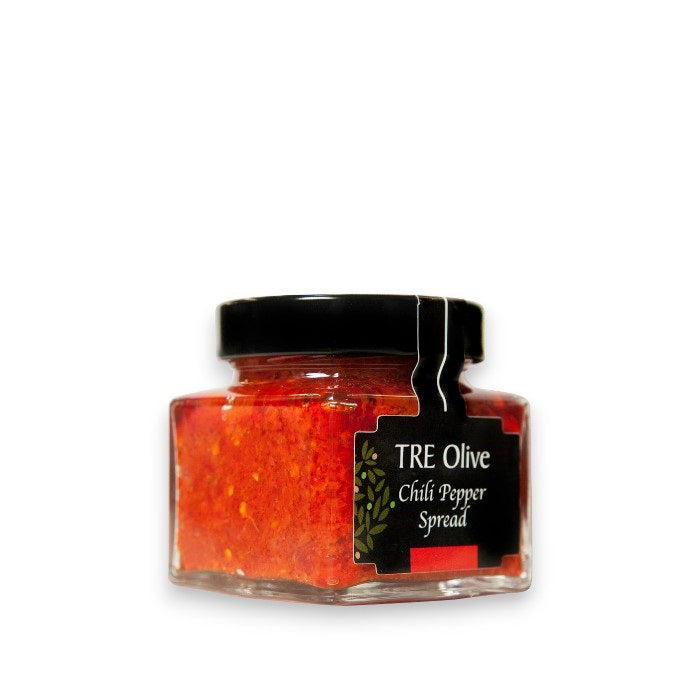 A small glass jar with a black lid contains TRE OLIVE - CALABRIAN CHILI PEPPER SPREAD. The label is black with a green olive branch design and white text. Made in Italy, the bright red spread is visible through the jar, promising rich flavor.