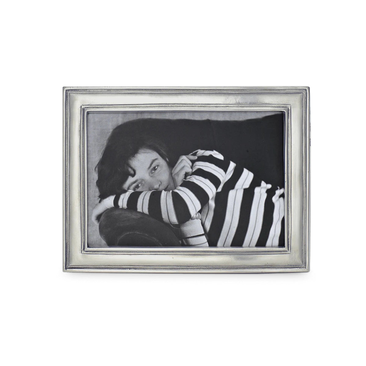 A black-and-white portrait of a dark-haired person in a striped shirt, lying on their side with arms crossed, is displayed in the MATCH - LUGANO PEWTER PHOTO FRAME by MATCH, featuring an elegant wood-backed silver pewter design.