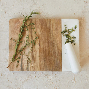 The CHEESE BOARD WITH MARBLE PESTLE by CREATIVE COOP features a rectangular two-tone design: natural mango wood on the left with unique grain patterns and a smooth white marble inlay plus a small handle on the right.