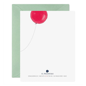 A stylish green envelope crafted from luxurious paper, partially open to showcase the REALLY HAPPY BIRTHDAY GREETING CARD by E.FRANCES PAPER. The card features a minimalistic design of a red balloon gracefully floating at the top against a white background, with branding details elegantly placed at the bottom, embodying the charm of handcrafted watercolor greeting cards.