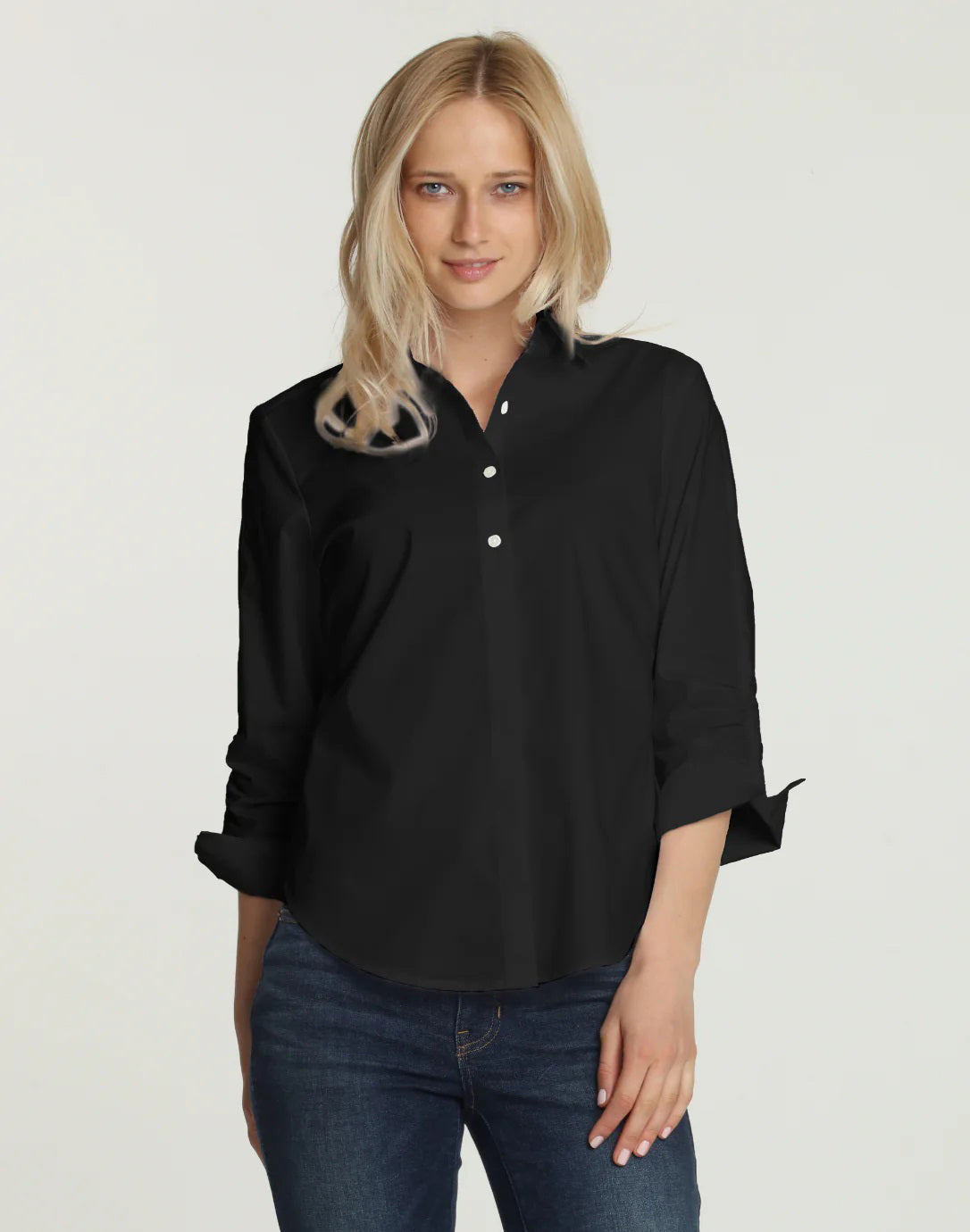 A person wearing the HINSON WU - ZOEY SHIRT in black, with the sleeves rolled up and paired with blue jeans. The image highlights the classic tailored design from shoulders down against a plain white background.