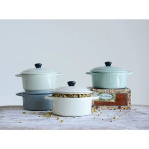 The CREATIVE COOP MINI STONEWARE BAKER WITH LID set includes four mini bakers in gray, mint green, light green, and off-white. Perfect for individual servings, each has a black knob on its lid and dual handles. They are arranged in a neat 2x2 grid.