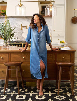 The FRANK & EILEEN Rory Maxi Shirtdress in Famous Denim is a full-length button-up dress featuring a collar, rolled-up sleeves to mid-length, and a single chest pocket. Its sleek, minimalist design embodies that California chic look against a plain white textured background.