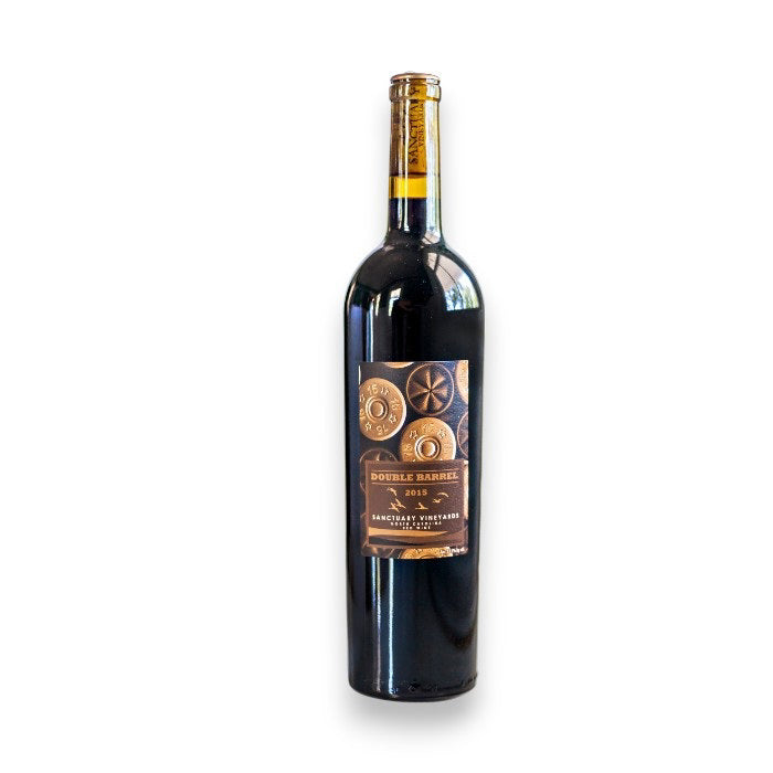 A 2019 bottle of "Sanctuary 'Double Barrel' Tannat Petit Verdot" from Freedom Beverage, featuring circular rustic designs that highlight its North Carolina origins, elegantly contrasts a plain white background.