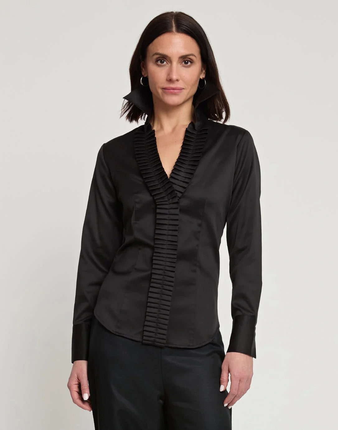 A woman with shoulder-length dark hair is shown from the back, wearing a white HINSON WU - MAYA Long Sleeve Cotton Satin Shirt and black pants. She is standing against a plain, light-colored background.