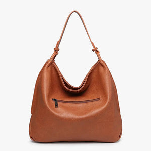 The JEN & CO RUSTIC TOTE is crafted from brown vegan leather and features a relaxed, slouchy shape. Its simple and elegant design includes a single strap attached at both sides, along with an inner compartment for added functionality, all set against a plain light background.