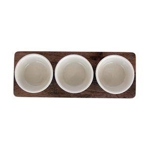 Three small stoneware bowls are placed on a rectangular mango wood tray. The bowls are evenly spaced and aligned in a row. The MANGO WOOD TRAY WITH BOWLS by CREATIVE COOP features a minimalist design with a natural and rustic aesthetic.