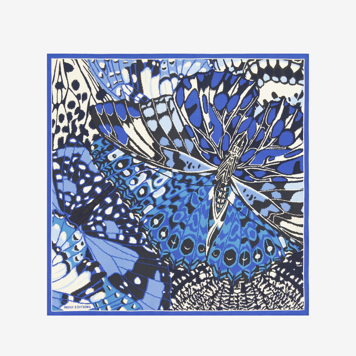 A close-up of the INOUI EDITIONS PAPILLON silk scarf in blue, featuring a smooth, shiny texture and abstract butterfly-inspired pattern in blue, black, and cream—a versatile accessory crafted in India by INOUI.