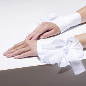 A pair of CATHERINE OSTI - BEATRICE CUFFS in white, medium size, featuring symmetrical, handmade pleated ruffles. Crafted from delicate, sheer fabric, the gathered ruffles spread outwards to provide a formal and decorative appearance, making them an elegant fashion accessory.