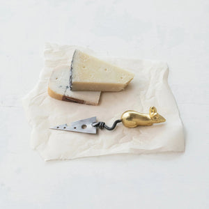 The CHEESE KNIFE WITH MOUSE HANDLE by CREATIVE COOP is a unique stainless steel cheese knife featuring a whimsical, golden rat-shaped handle and a triangular blade with three circular holes of varying sizes. This luxurious kitchen utensil adds an artistic touch, making it a standout addition to any cheese board.