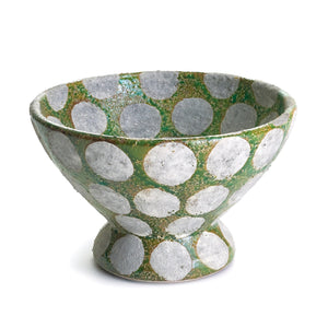 The NAPA HOME AND GARDEN - KILEY FOOTED BOWL makes a charming centerpiece with its wide base, flared sides, and green and white polka dot pattern. The textured spots on the green backdrop emphasize its rustic, mid-century pottery style.