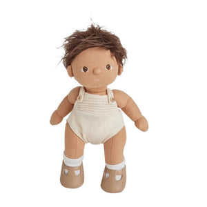 A DINKUM DOLL from OLLI ELLA USA features soft brown hair and comes dressed in a white knit romper paired with brown shoes. This charming doll has an embroidered face with brown eyes, a small nose, and a gentle smile. Its posable body makes it perfect for imaginative playtime, and it is posed standing upright.