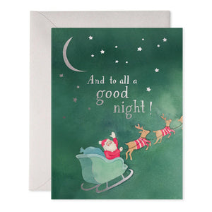 The TO ALL A GOOD NIGHT HOLIDAY CARD from E.FRANCES PAPER features a delightful Santa illustration in a sleigh pulled by reindeer, set against a green background. The partially visible white envelope adds an extra touch of charm. At the bottom, you'll find the logo, contact information, barcode, and a whimsical whale illustration.