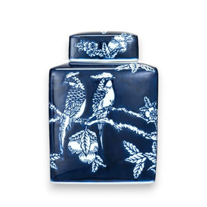 The HAND PAINTED CERAMIC GINGER JAR by CREATIVE COOP is a rectangular, dark blue and white ceramic piece adorned with white illustrations of two birds perched on a tree branch, surrounded by floral patterns. The jar includes a matching lid decorated with similar intricate designs.