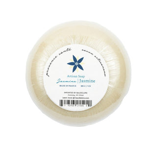 A hexagonal blue box of Baudelaire Jasmine 7 oz Boxed Bath Bar, enriched with shea butter. The box features a large, stylized white flower design and text such as "Jasmine," "Savor artisanaux," "Artisan Soap," and "Made in France.