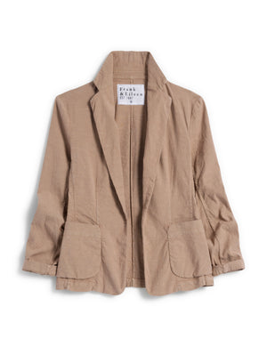 A beige linen blazer, named the "Dublin Tailored Blazer in Linen" from Frank & Eileen, is displayed against a white background. This versatile piece features a relaxed fit with a notched lapel collar and two front flap pockets. The casual, slightly wrinkled texture adds to its charm. Inside, the branding label reads "Frank & Eileen EST 1947".