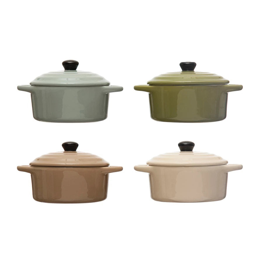 Four "1 CUP MINI BAKER WITH LID" casserole dishes by CREATIVE COOP are arranged in a 2x2 grid. The top left is light blue, the top right is olive green, the bottom left is light brown, and the bottom right is beige. Each piece of this versatile bakeware features a black knob on its lid.