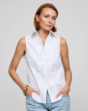 A woman with long hair wears the HINSON WU Lilith Sleeveless Shirt, made from stretch polished cotton with pleats and a beige belt, against a gray background. She exudes confidence as she gazes at the camera, highlighting the shirt's versatility.