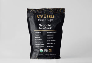 A black package of STRUESLI - CACAO + COFFEE GRANOLA against a white background. The front of the package lists features such as tiger nuts, pecans, walnuts, prebiotic, no sweeteners, no grains, and artisan coffee. Text at the bottom mentions that the organic granola is plant-based and keto-friendly.