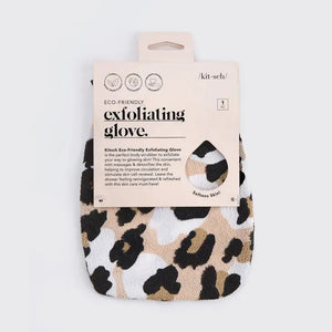 Image of a KITSCH ECO FRIENDLY EXFOLIATING GLOVE. It features a beige, black, and dark brown leopard print pattern. The eco-friendly packaging is beige with text indicating the body scrubber is designed for softening skin. The glove hangs on a peg against a plain backdrop.