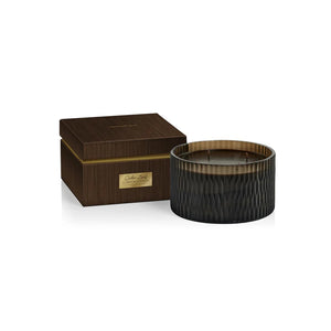 A cylindrical, dark green candle with a textured surface sits next to a matching dark brown, wood-textured box with a gold label. The box lid reads "ZODAX." The candle features five wicks and boasts fragrance notes of Cedar Leaf and Hinoki Cypress, with the box label reading "5 WICK CANDLE - CEDAR LEAF & HINOKI CYPRESS" to indicate the scent.