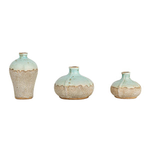 Set against a plain white background, the CREATIVE COOP DISTRESSED TERRACOTTA VASE - LARGE features a textured light brown base with a smooth pale aqua upper section. These charming rustic pieces vary in shape and size from tall and slender to short and round.