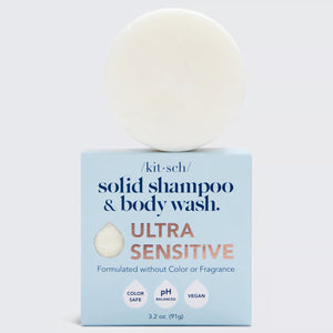 A circular, white 2-in-1 cleansing bar is balanced on top of a light blue box. The box reads, "KITSCH Ultra Sensitive Shampoo & Body Wash Bar. ULTRA SENSITIVE, Fragrance Free Shampoo. Formulated without Color or Fragrance." The product is 3.2 oz (91g), color safe, pH balanced, and vegan.