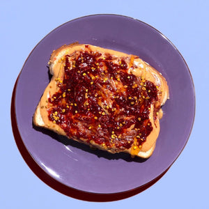 A jar of CHIA SMASH - STRAWBERRY CHIA JAM with zero added sugar. The jar boasts a red lid and a label showcasing a large strawberry illustration, along with the text "No Sugar Added!" and "Non-GMO Project Verified" certification. Made from upcycled fruit, this 8 oz (227g) jam is both paleo and vegan friendly.