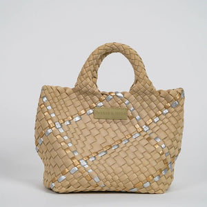 A woman with long brown hair, in a sleeveless cream knit top and blue jeans, holds a PARKER AND HYDE - MINI WOVEN TOTE BAG. The hand-woven tote by PARKER & HYDE features a subtle checkered pattern with light blue accents.