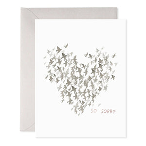 The STARLINGS CONDOLENCE GREETING CARD by E.FRANCES PAPER beautifully features a heart shape created from small bird silhouettes in calming gray tones. The words "So Sorry" are elegantly inscribed at the bottom right corner, complemented by handcrafted watercolor elements that enhance its charm. An envelope is partially visible in the background, adding to its presentation.