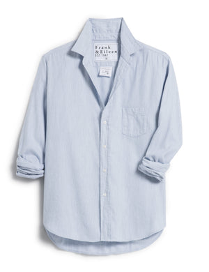 The Eileen Relaxed Button Up Shirt in Gray Blue by Frank & Eileen features a chest pocket, rolled-up sleeves, and bust-flattering button placement. Its inside label says "Frank & Eileen EST. 1947," and it is shown laid flat against a white background.